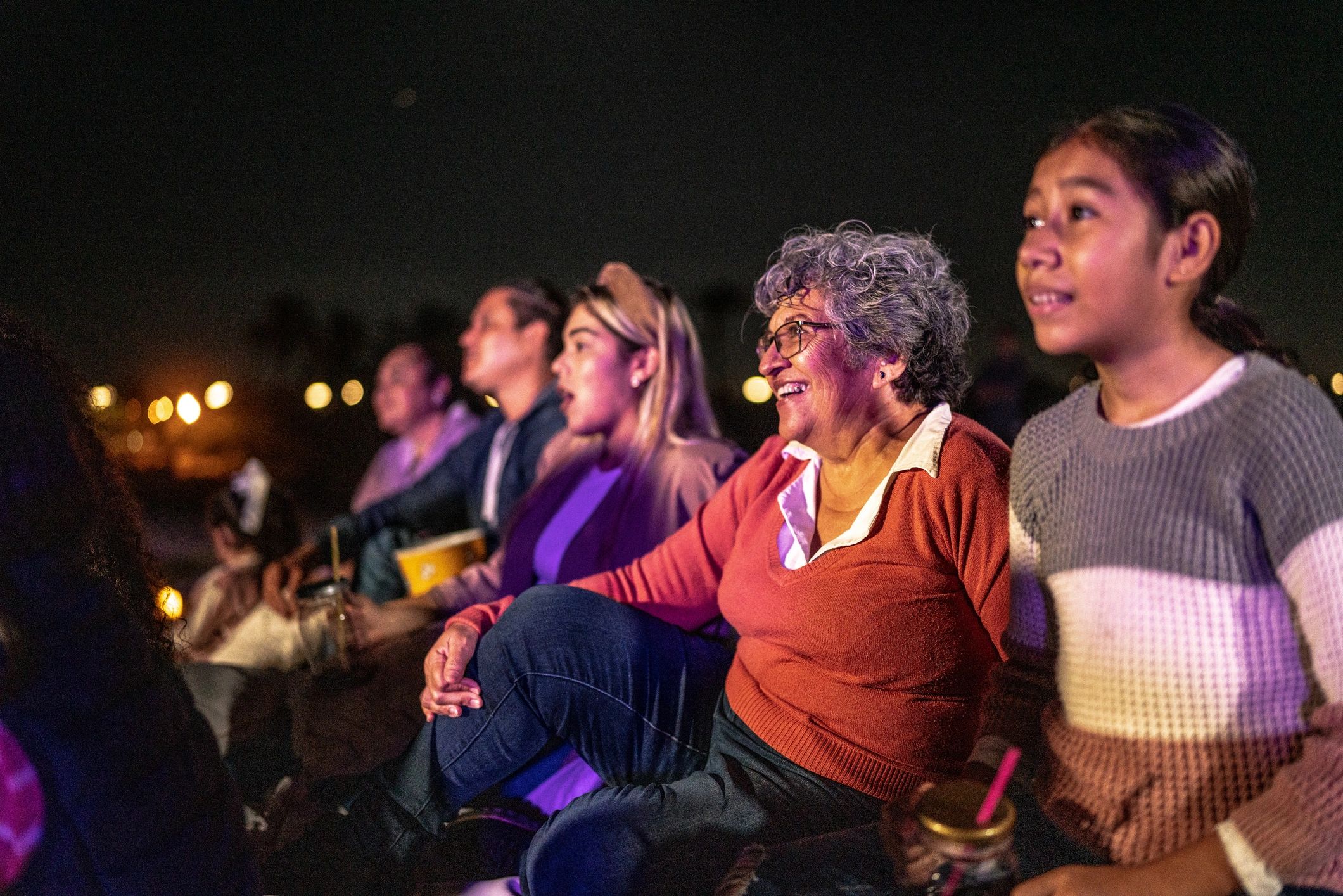 Audience seated outdoors with soft lights in the background