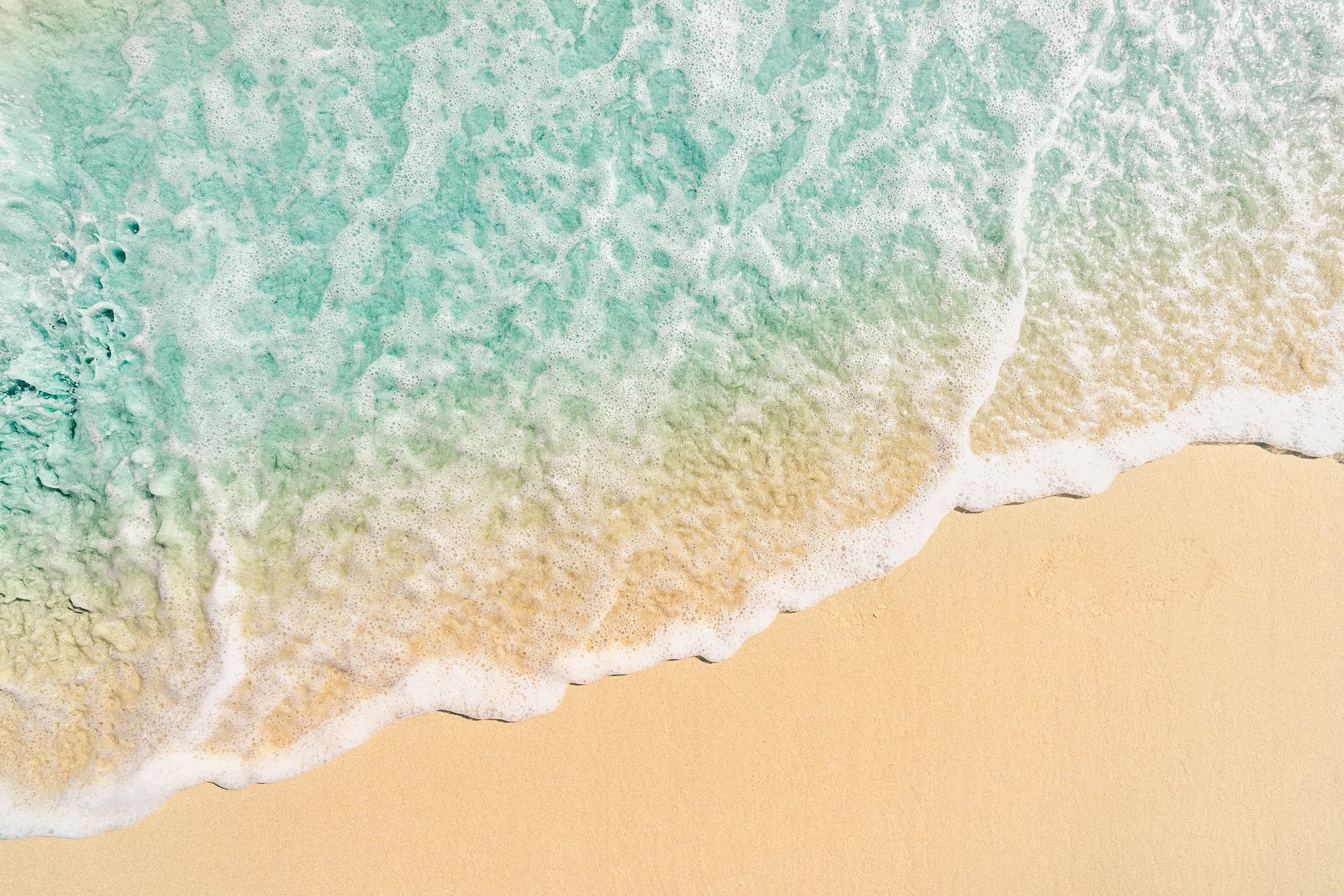 Top-down view of a wave washing over smooth sand