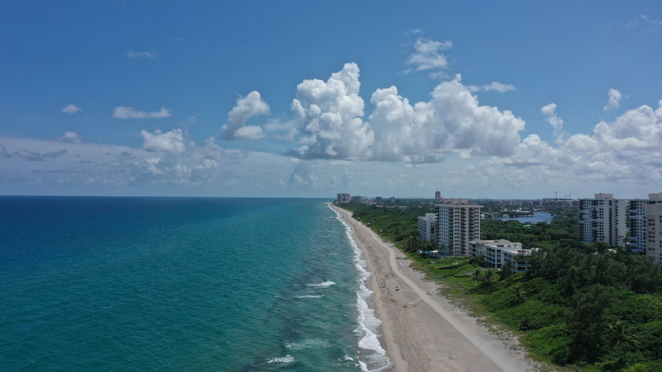 Aerial view of coastline with ocean and sandy beach under a blue sky